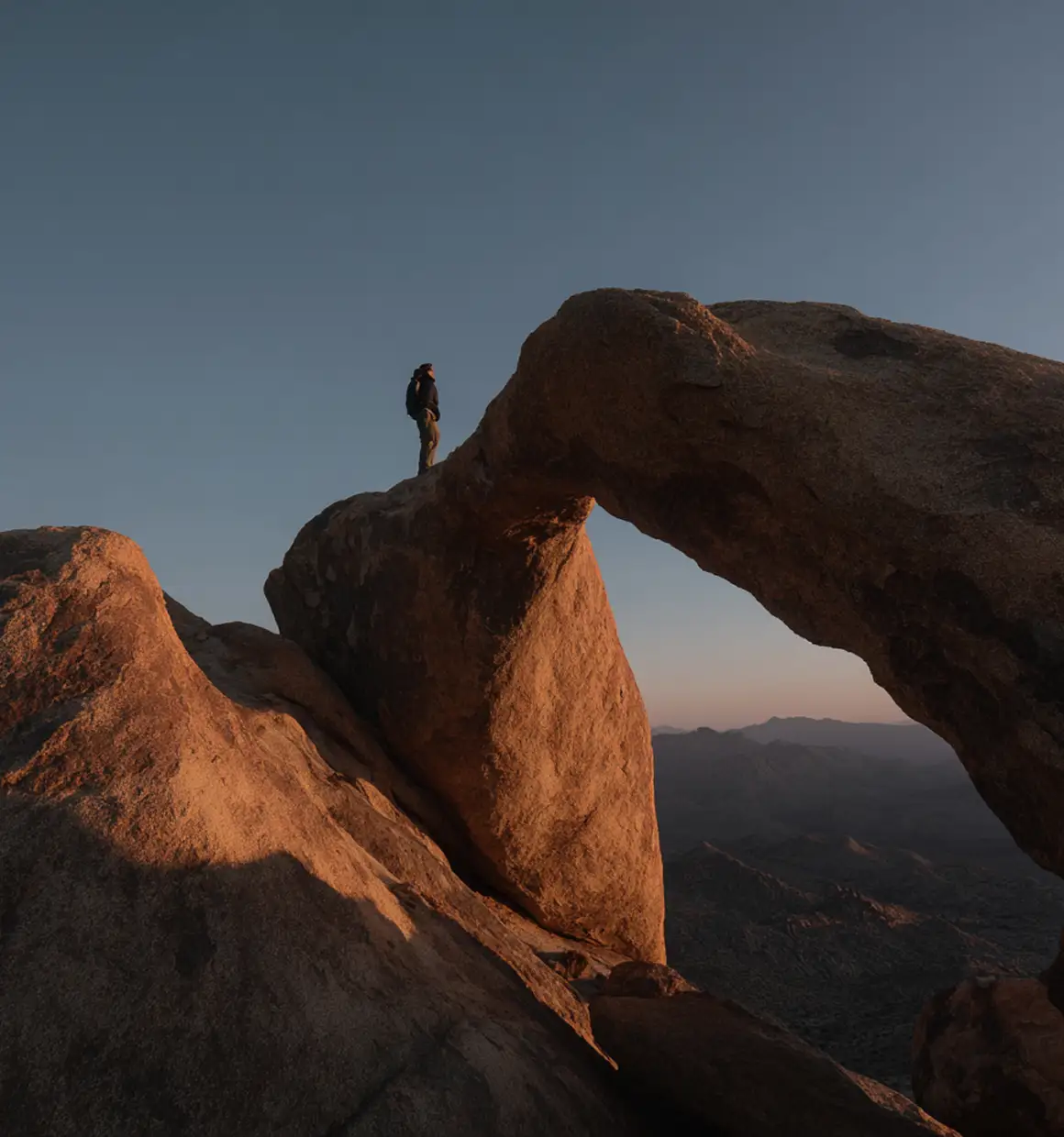 Suplar Athletics explorer on rock arch during sunset adventure